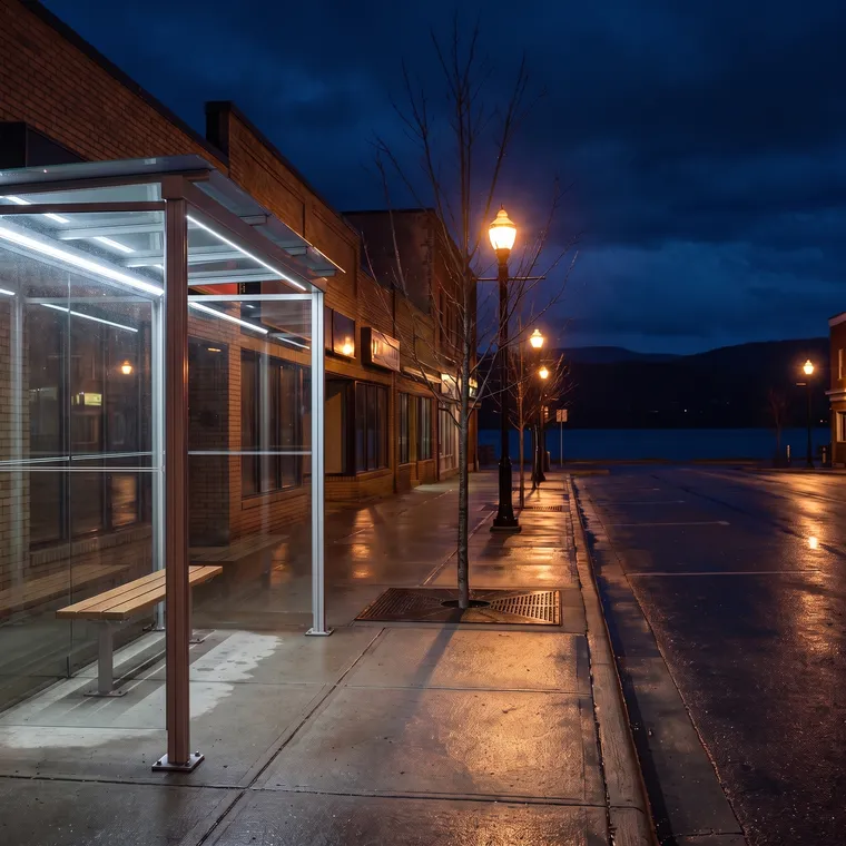 Empty bus shelter on a wet street at night